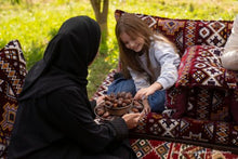 Child taking a date from a woman - Image credit Saudi Tourism Authority